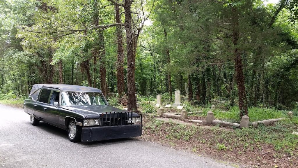 cadillac hearse with wrecker pumper parked at cemetery
