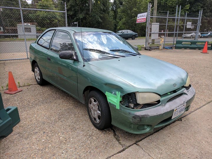 ugly beat up hyundai car with tape holding the bumper and other parts on