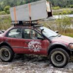 red lifted geo metro sedan with what looks like a fridge on the roof at the gambler 500