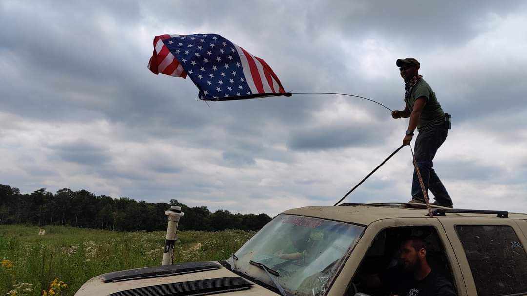 Matthew Woo waving an American flag from the roof of a car at the gambler 500