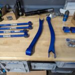 hardrace rear control arm kit for a subaru forester sg uninstalled on a wood bench
